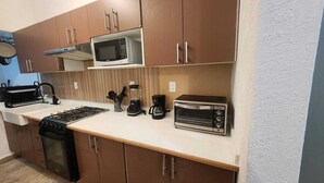 Cocina compacta equipada con estufa a gas, microondas, tostadora y cafetera.