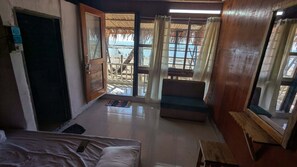 A room with a bed, a bench, a small table, and a view of the beach through a large window. - Beach Valley Eco Resort Saint Martin (Saint Martin's Island)