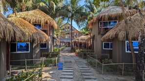 Un resort con cabañas de techo de paja, un edificio central y un sendero despejado.