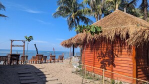 A beach hut with a thatched roof, wooden benches, and a wooden fence. - Beach Valley Eco Resort Saint Martin (Saint Martin's Island)