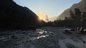 Ein Fluss mit Steinen und eine kleine Hütte im Vordergrund.