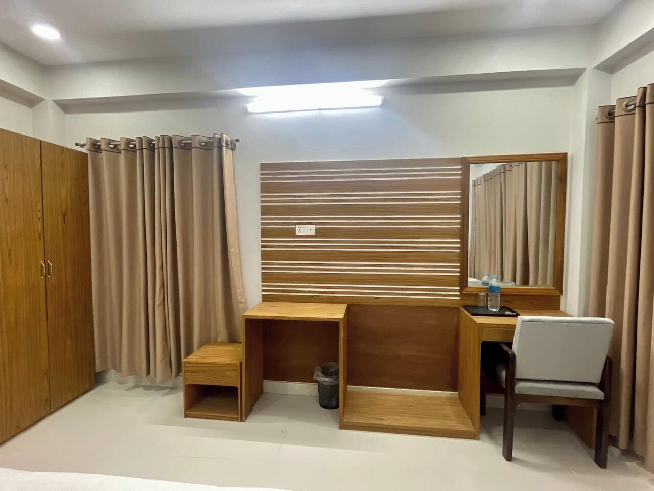 Un dormitorio con escritorio de madera, una silla, armario y espejo.
