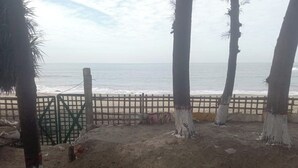 A sandy beach area with a wooden fence and palm trees. - Shuktara Beach Resort Saint Martin (Saint Martin's Island)