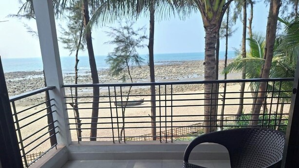 A balcony with a view of a beach, a chair, and a railing. - Shuktara Beach Resort Saint Martin (Saint Martin's Island)
