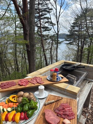 An outdoor cooking area with a grill, various meats, vegetables, and condiments. - The view of the lake and snow-capped mountains is breathtaking! Limited to one pair per day. A dedicated butler is always on hand to ensure a safe stay. Includes choice of breakfast & 15 min drive to 5 ski resorts! (上水内郡信濃町野尻)