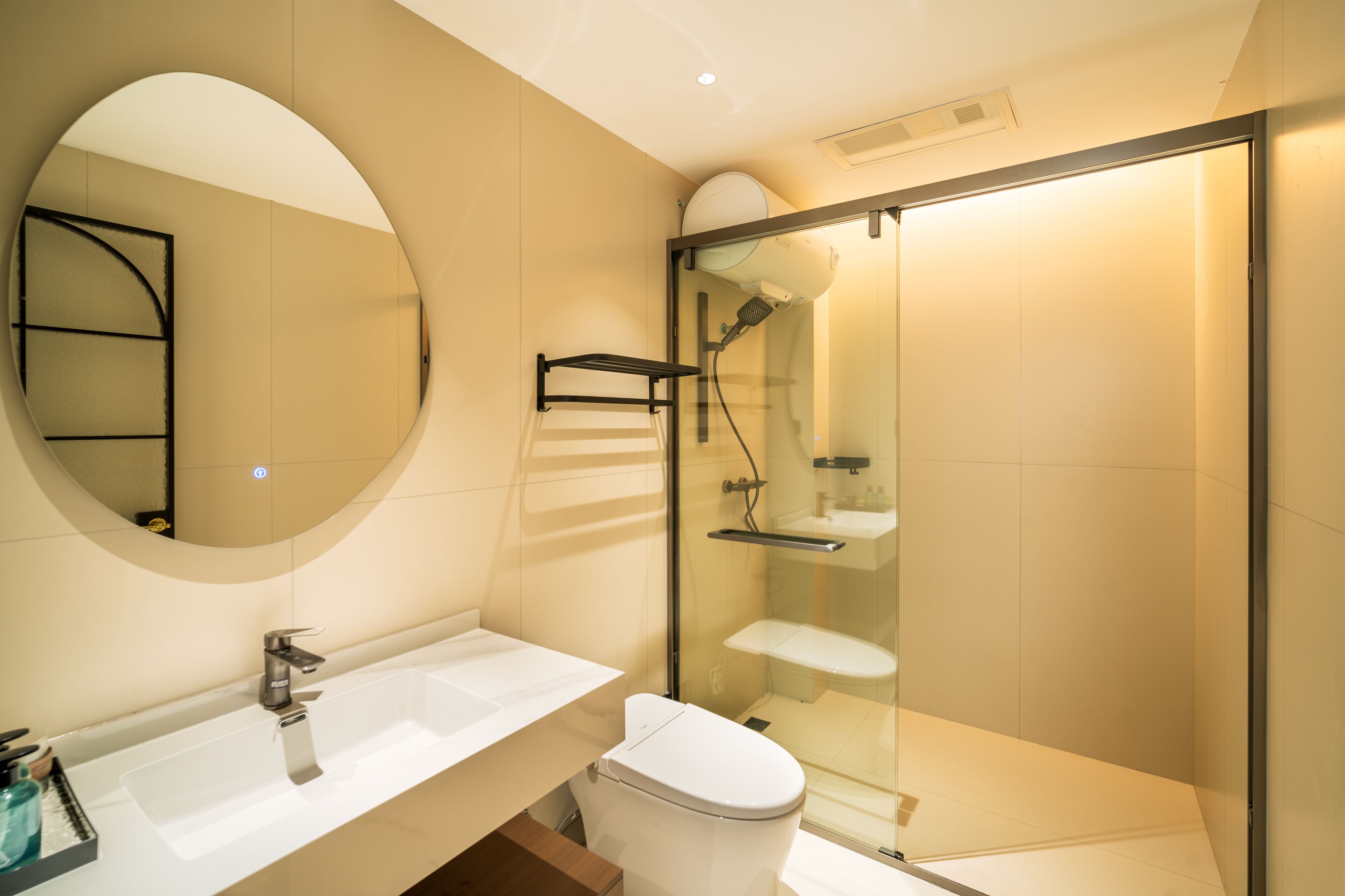 Un baño moderno con ducha envuelta en vidrio, un lavamanos blanco y un espejo grande.