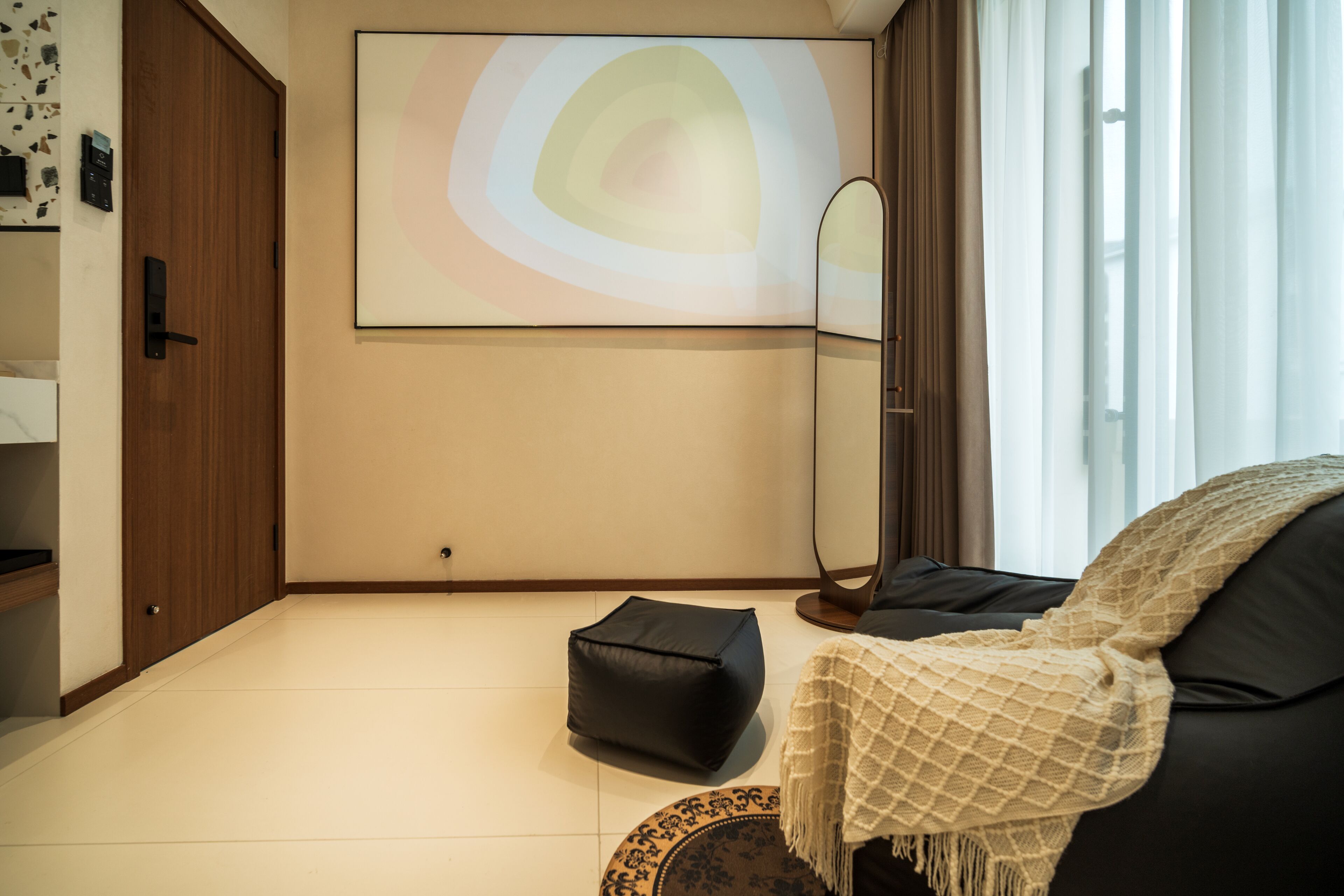 A modern living room with a black sofa, a throw blanket, a floor lamp, and a large abstract painting on the wall.