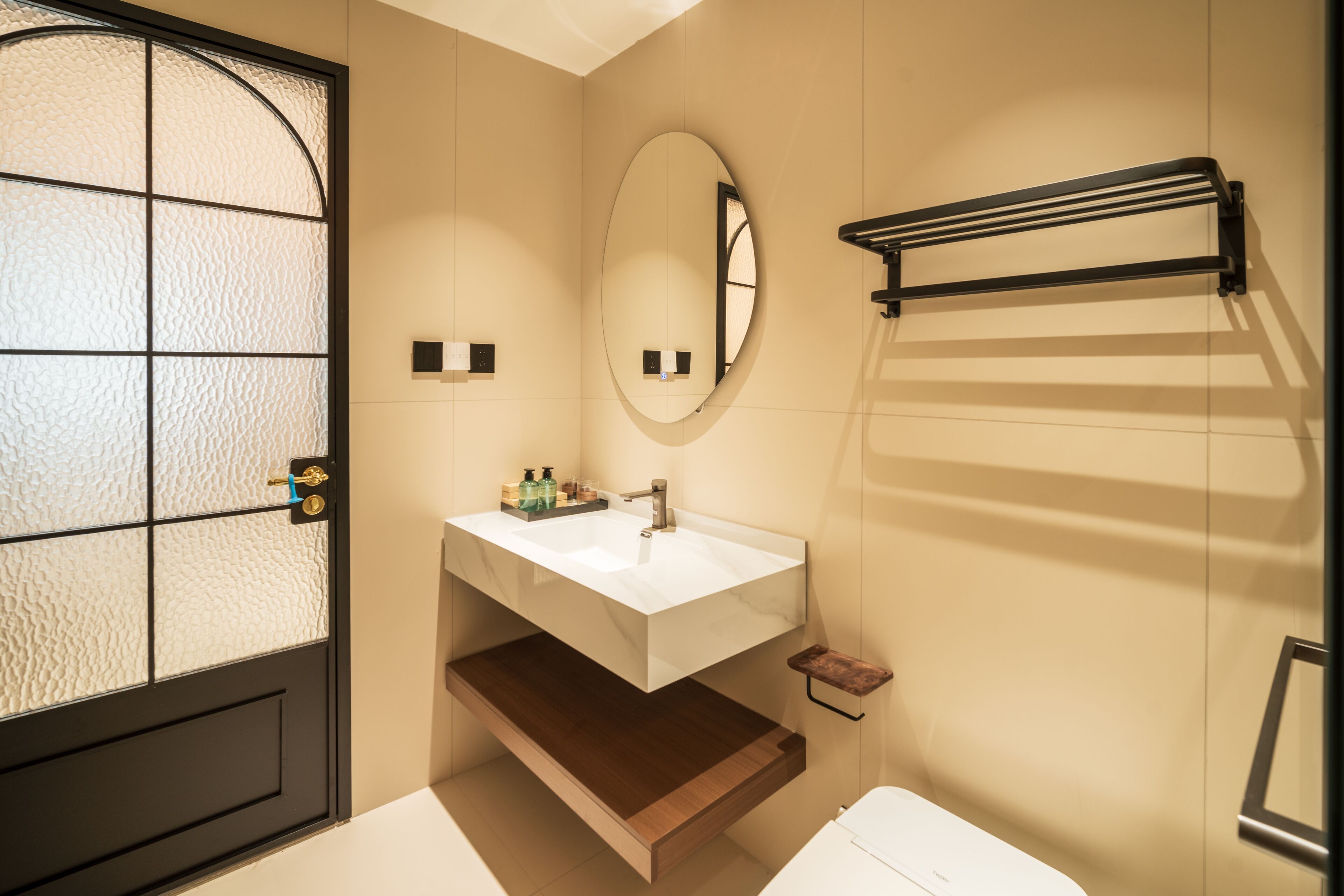 A bathroom with a white sink, a mirror, a towel rack, and a toilet.