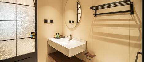 A bathroom with a white sink, a mirror, a towel rack, and a toilet.