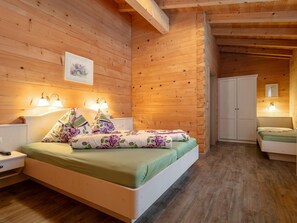 A wooden-paneled bedroom with a bed, bedside lamps, a wardrobe, and a framed picture on the wall. - Holiday Home in Salzburg with Alpine View (Leogang)