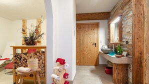 A cozy room with a wooden bench, a wooden towel rack, a wooden door, and a stone wall. - Holiday Home in Salzburg with Alpine View (Leogang)
