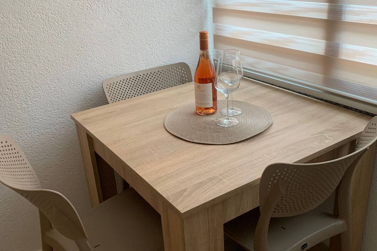 A wooden table with a bottle of wine and a glass on a woven placemat.