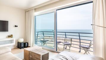 Un salón moderno con un amplio ventanal corredero que da a un balcón con vistas al mar.
