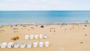 Una playa con cabañas blancas y gente relajándose.