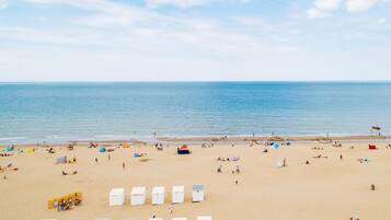 Una playa con cabañas blancas y gente relajándose.