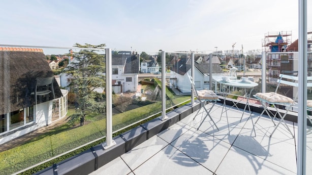 A rooftop terrace with a clear view of surrounding buildings and a construction site. - Cosy flat with beautiful terrace (Koksijde)