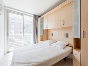 Ein modernes Schlafzimmer mit einem großen Bett, einem Einbauschrank und einer Schiebetür zu einem Balkon.