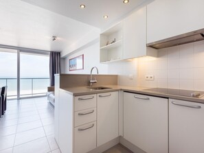 Eine moderne Küche mit weißen Schränken, einer Edelstahl-Spüle und Meerblick durch große Fenster.