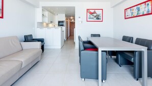 En modern lägenhet med matplats, pentry och ett vardagsrum med soffa och fåtöljer.