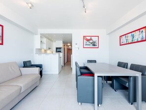 Eine moderne Wohnung mit Essbereich, Küchenzeile und einem Wohnzimmer mit Sofa und Sesseln.