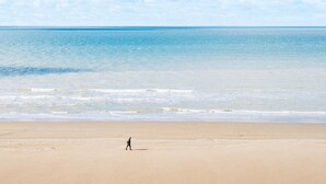 A beach with a person walking on the sand. - Wake up to sea views (Koksijde)