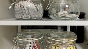A storage shelf with four glass jars containing various items.