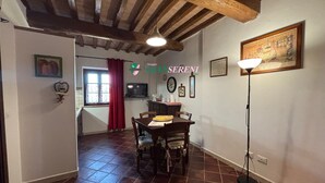 A dining area with a wooden table and chairs, a red curtain, and a painting on the wall. - 4sleeping places with swimming pool, parking space (Campiglia Marittima)