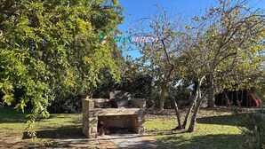 An outdoor barbecue area with a stone-built grill, surrounded by trees and grass. - 4sleeping places with swimming pool, parking space (Campiglia Marittima)