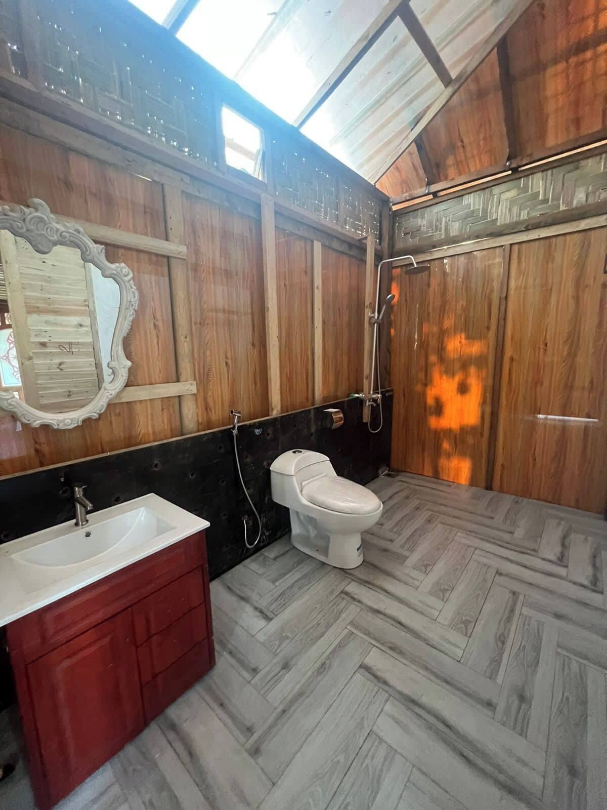 A bathroom with a wooden interior, a white toilet, a red vanity, and a mirror.