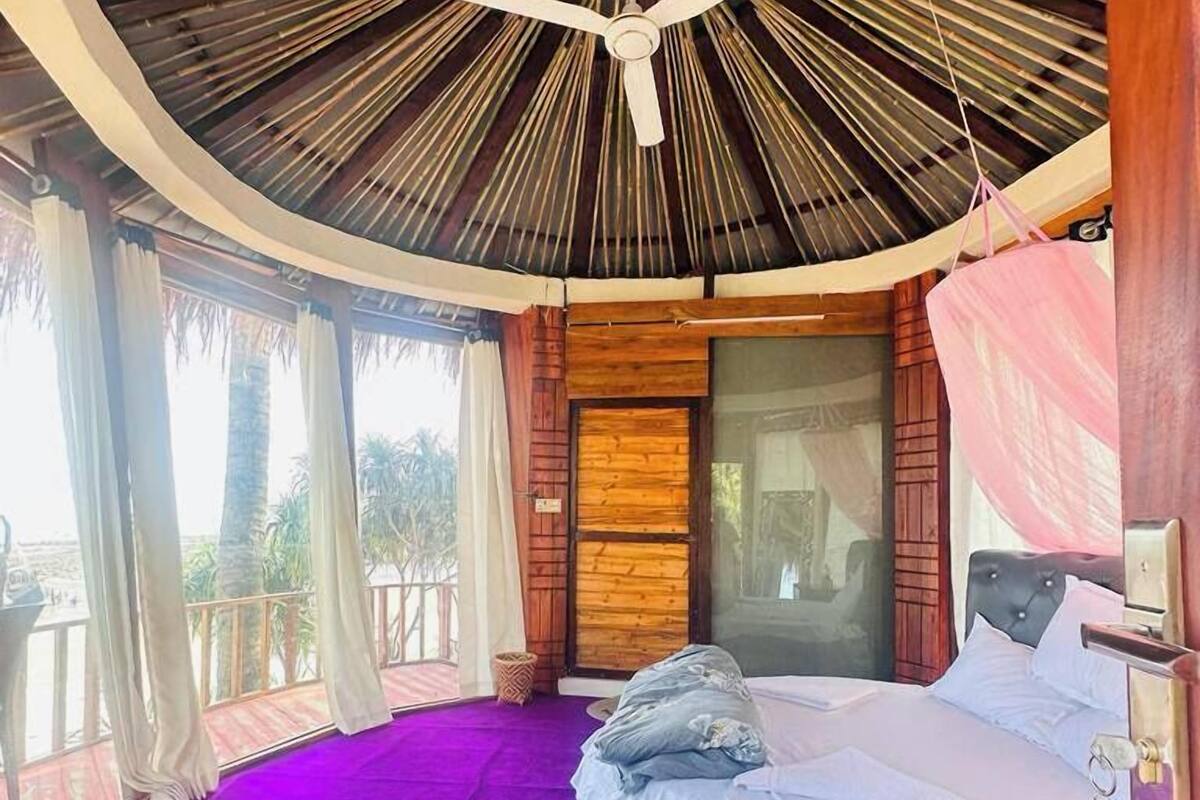Ein runder Raum mit einem Bett, einem Deckenventilator und einem Fenster.