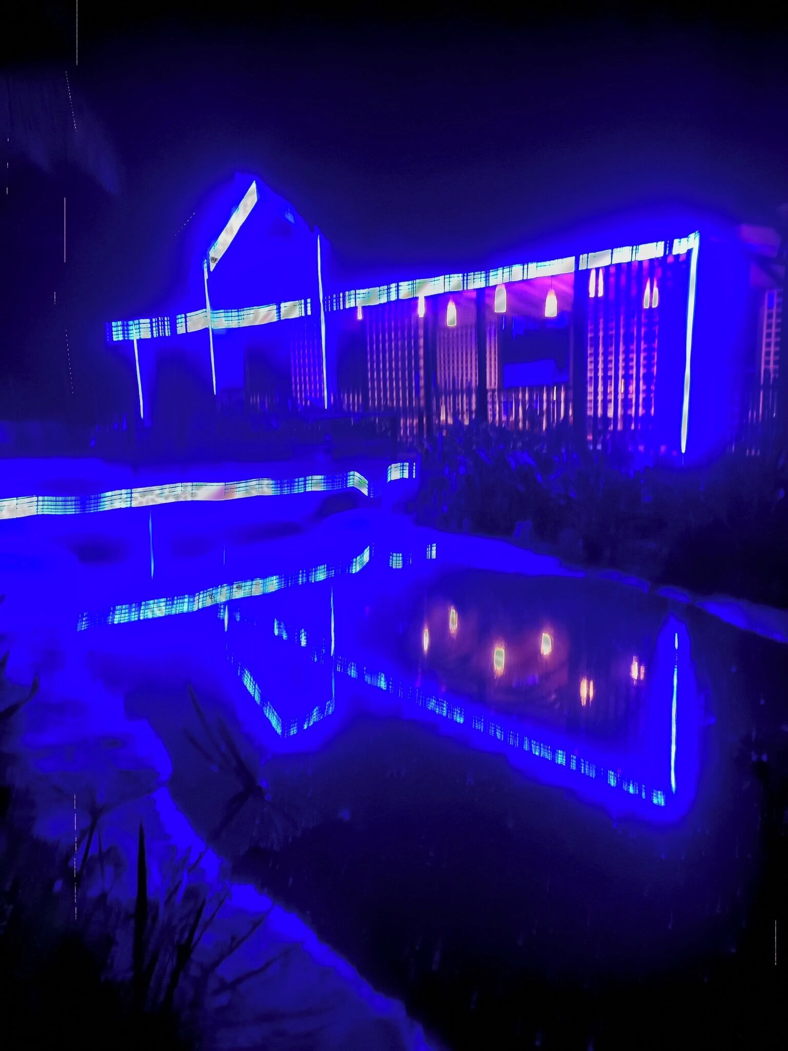 A building with a modern architectural design, featuring a prominent overhang and a reflective pool in front.
