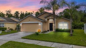 A residential house with a garage, a front lawn, and a driveway. - Spacious 5-bedroom Family Escape - Disney - Private Pool - BBQ (Davenport)