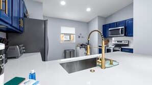 A modern kitchen with blue cabinets, a white countertop, and stainless steel appliances. - Spacious 5-bedroom Family Escape - Disney - Private Pool - BBQ (Davenport)
