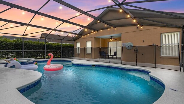 A pool area with a covered roof, inflatable swan floaties, and a sign indicating a 'like' service. - Spacious 5-bedroom Family Escape - Disney - Private Pool - BBQ (Davenport)