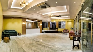 A spacious lobby with a reception desk, seating area, and a glass wall. - The Mewar Resort & Garden (Māvli)