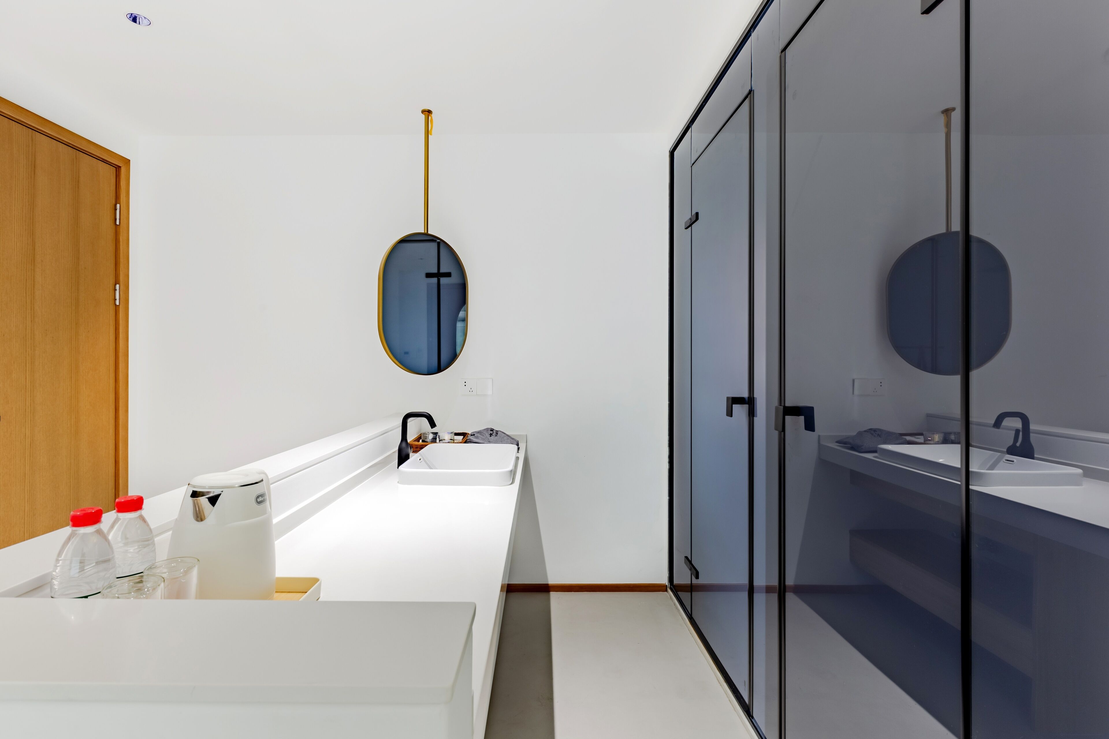 Un baño moderno con un lavamanos blanco, un espejo y una puerta de madera.