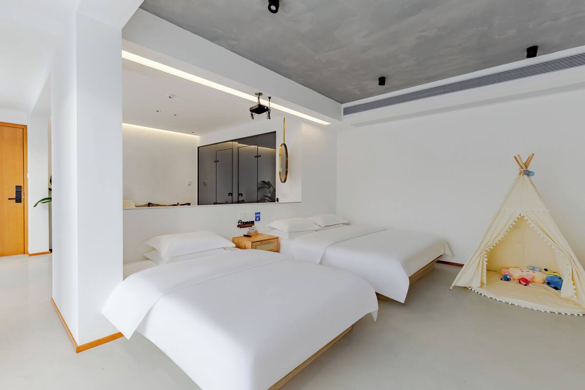 Un dormitorio moderno con dos camas, un espejo, una mesita de noche y una tienda tipi.