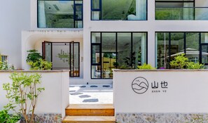 A modern building with a glass facade, a wooden entrance, and a logo with Chinese characters. - Shanye Guesthouse - Jingxian Shuimo Tingxi Scenic Area Branch (Xuancheng)