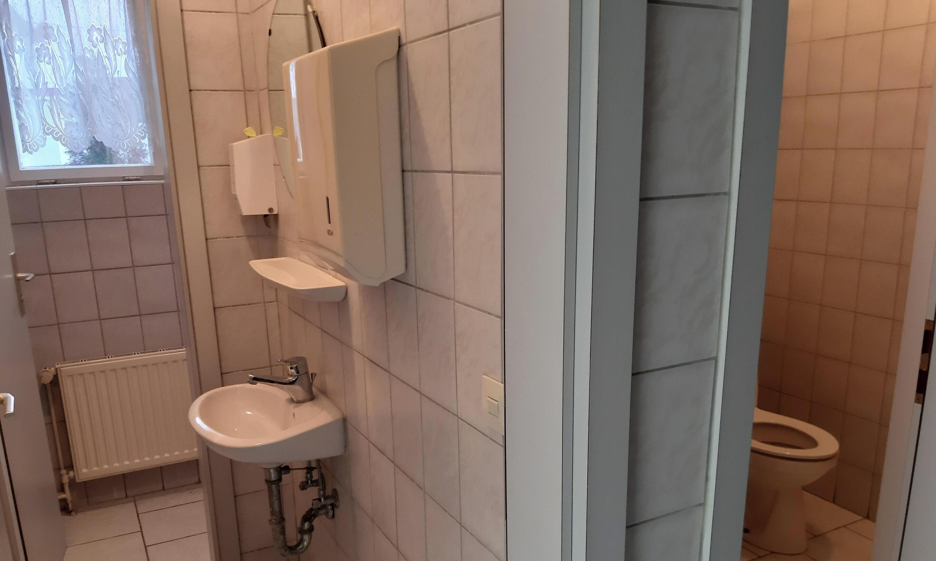 Un bagno con lavandino bianco, specchio e water.