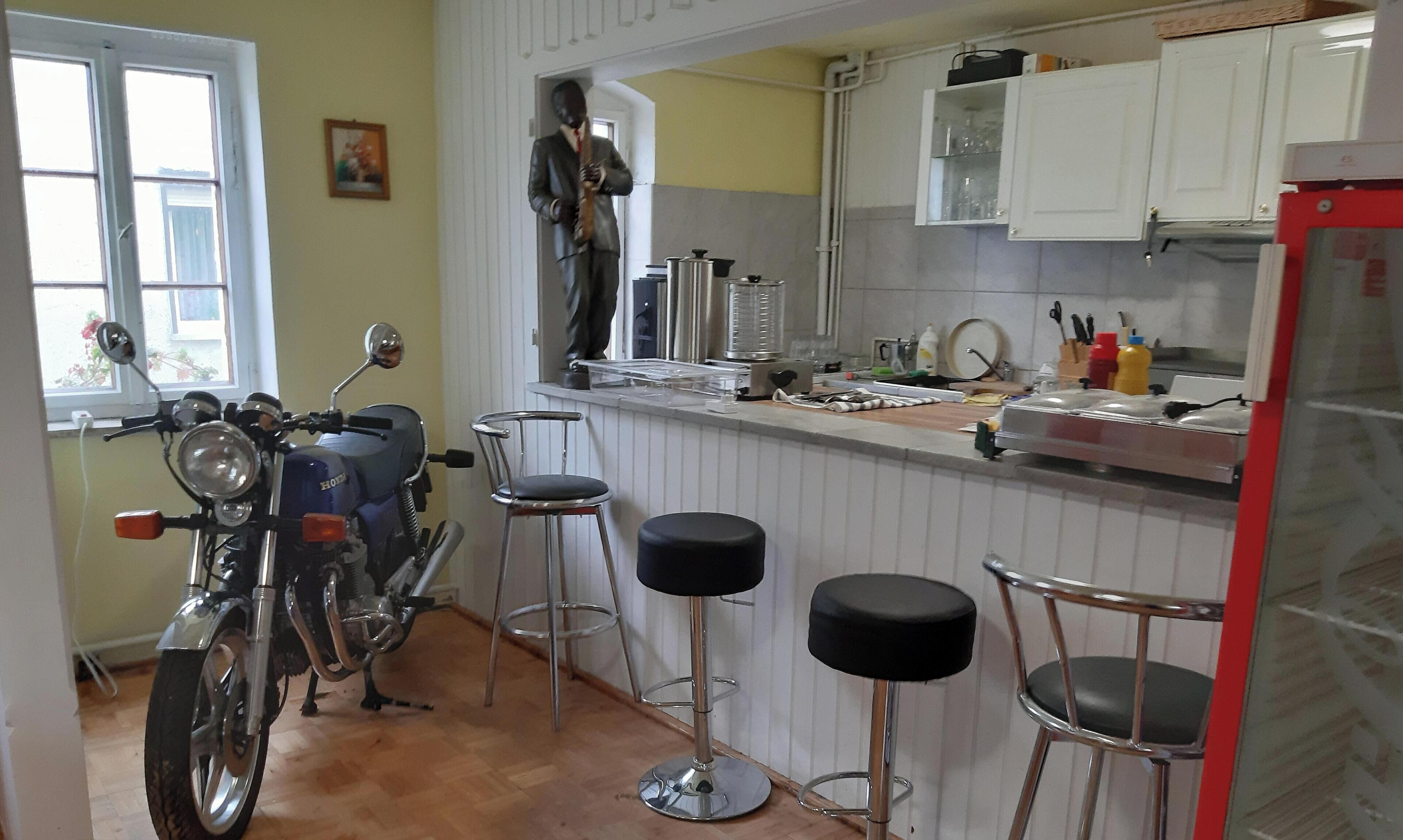 Eine Küche mit einem Motorrad, Barhocker und einem Kühlschrank.