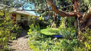 Ein Garten mit Kiesweg, einer Schaukel und einem Haus mit roter Tür.
