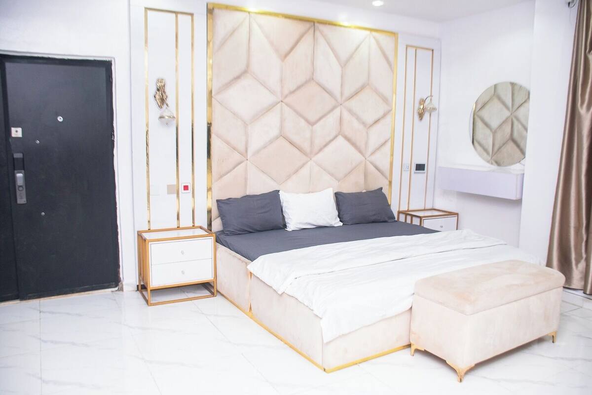 Une chambre moderne avec un grand lit, des tables de chevet, une armoire et un miroir rond.