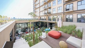 Um moderno conjunto de apartamentos com várias varandas, áreas de estar ao ar livre e vista para o horizonte da cidade.