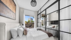 Ein modernes Schlafzimmer mit einem großen Bett, Stadtblick und einem Balkon.