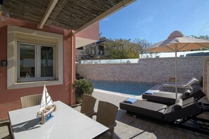 A poolside area with lounge chairs, a table, and a small sailboat model. - The Doctor's House- Vacation house in Kassiopi, Corfu (Kassiopi)