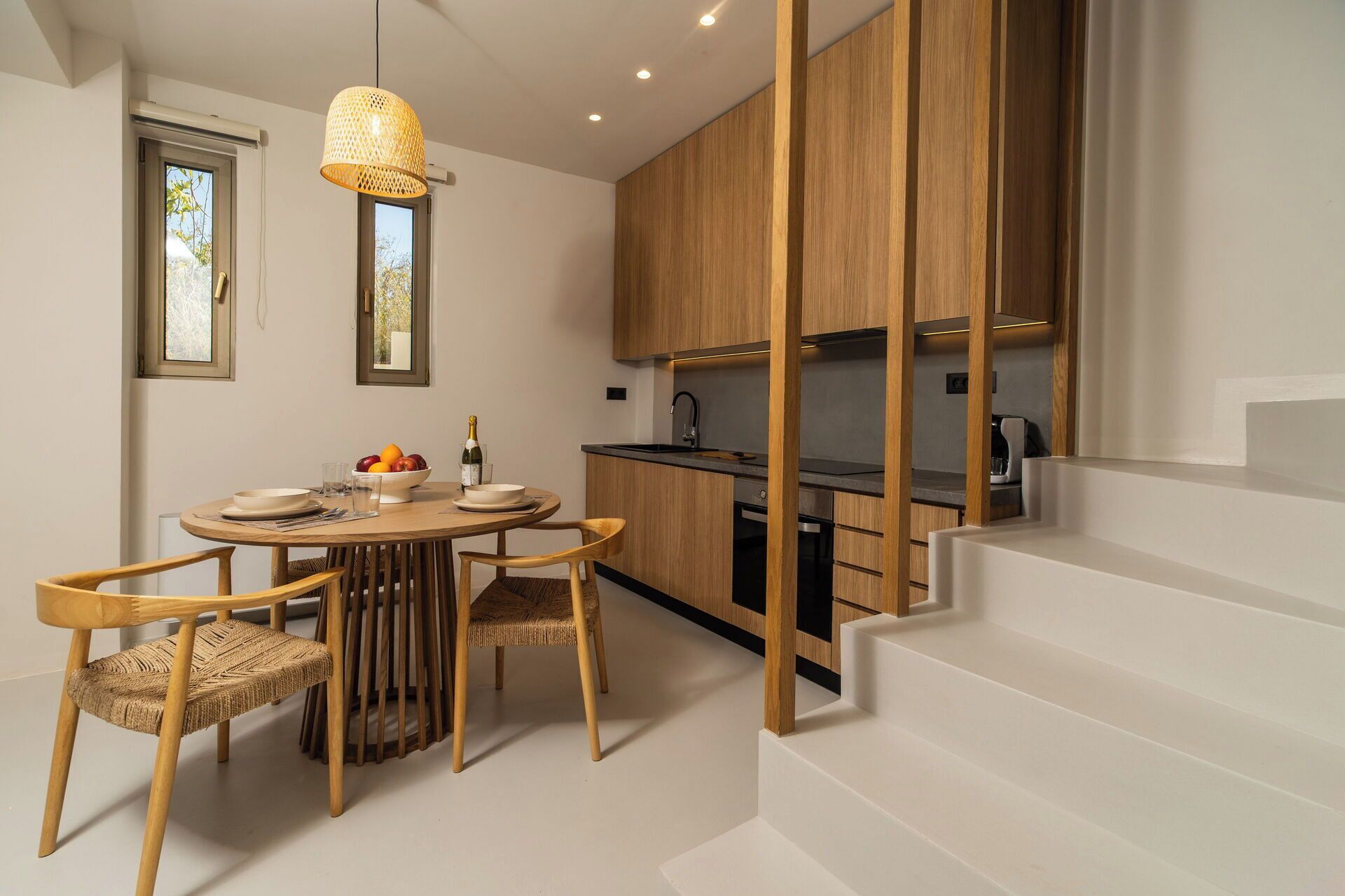 Una cocina moderna con armarios de madera, una mesa de comedor con sillas y una escalera.