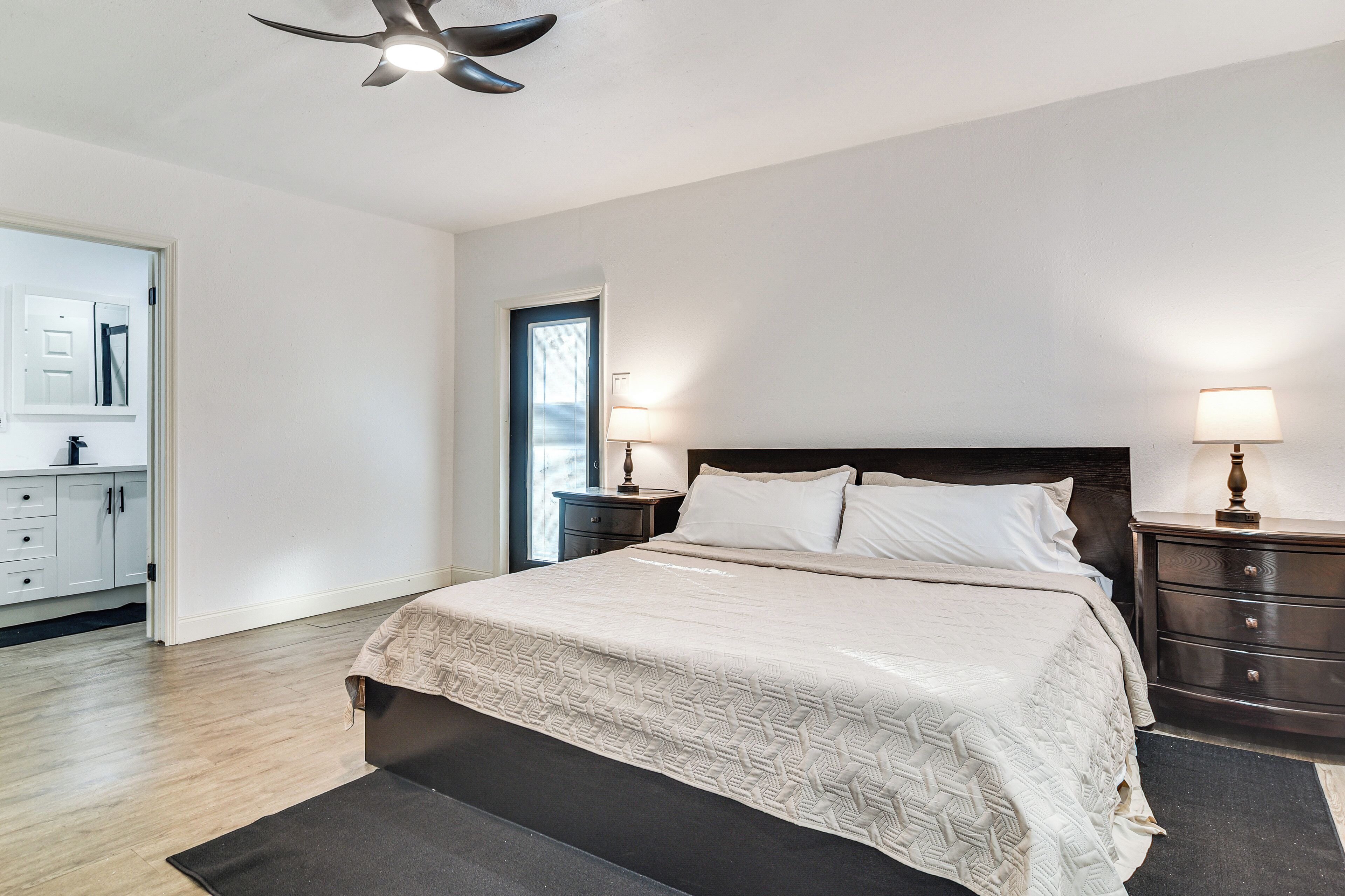 A bedroom with a bed, two bedside tables, a nightstand, a ceiling fan, and a window.