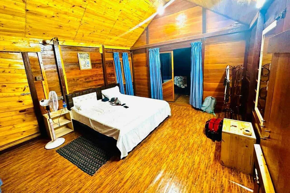 Ein Holzhütten-Zimmer mit einem Bett, einem Schreibtisch, einem Stuhl und einem kleinen Tisch.