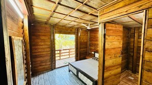 Eine Holzhütte mit einem Einzelbett, einem kleinen Tisch und einer Bank.