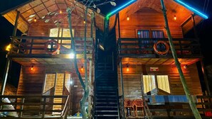 Eine Holzhütte mit zwei Etagen, jede mit einem Balkon und einer sichtbaren Treppe.